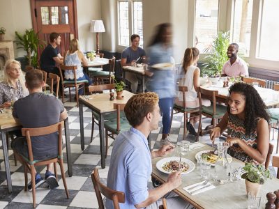 Customers Enjoying Meals In Busy Restaurant